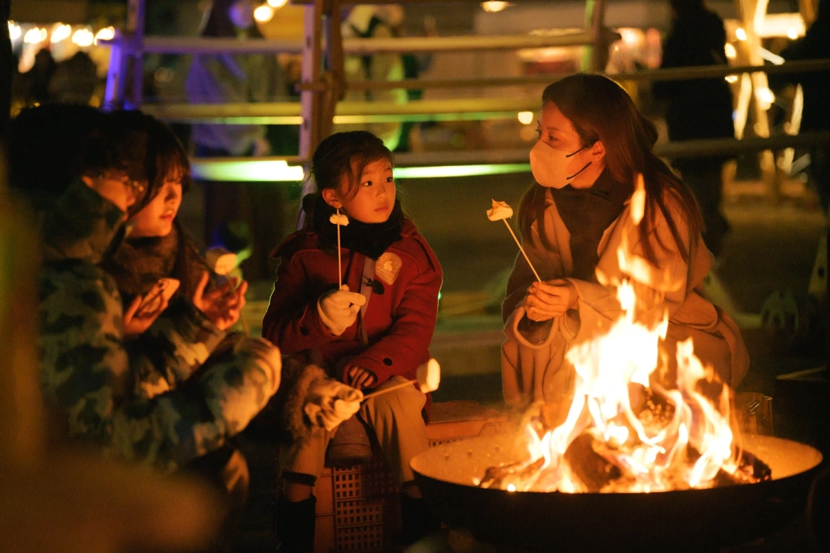 焚き火でマシュマロを焼く家族