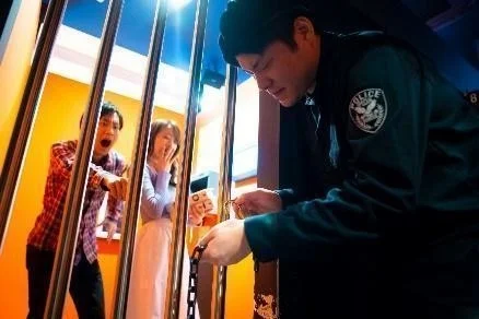 牢屋のような場所で驚く男女と警察官風の人物