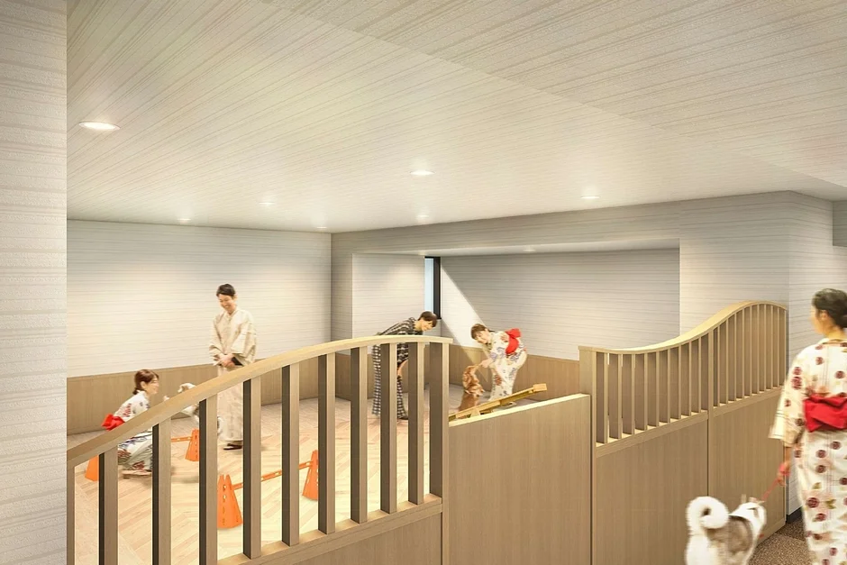 浴衣を着た人々が屋内の明るい空間で犬と触れ合っている様子。オレンジ色のコーンやスロープがあり、犬と遊んだり散歩させたりしている。ペット同伴可能な宿泊施設やドッグランのような施設に見える。