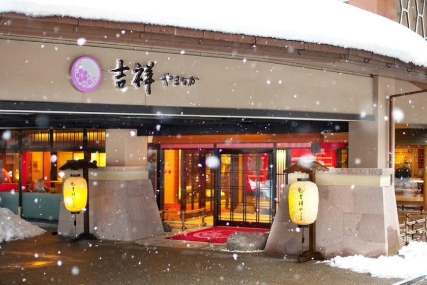 雪が降る日本の旅館「吉祥やまなか」の入り口を捉えた写真です