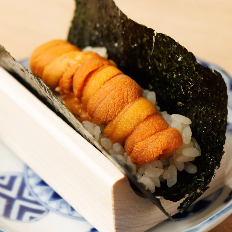 鮮やかなオレンジ色の新鮮なウニがたっぷり乗った海苔巻き寿司