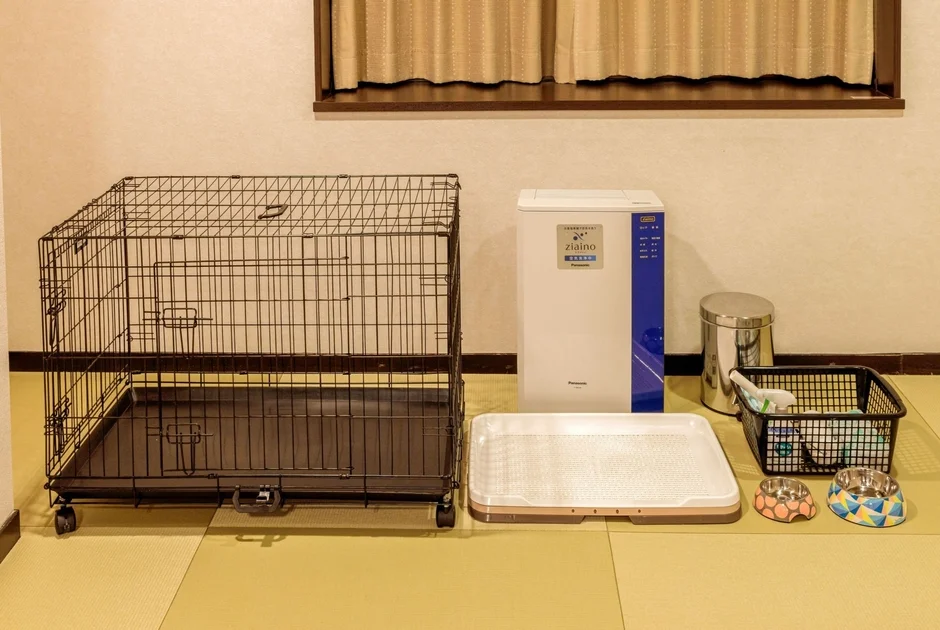 畳の部屋に設置された、犬用のケージ、パナソニックの空間除菌脱臭機ジアイーノ、トイレトレー、食器などのペット用品一式が写っています。ペットとの快適な暮らしをサポートするアイテムが揃っています。