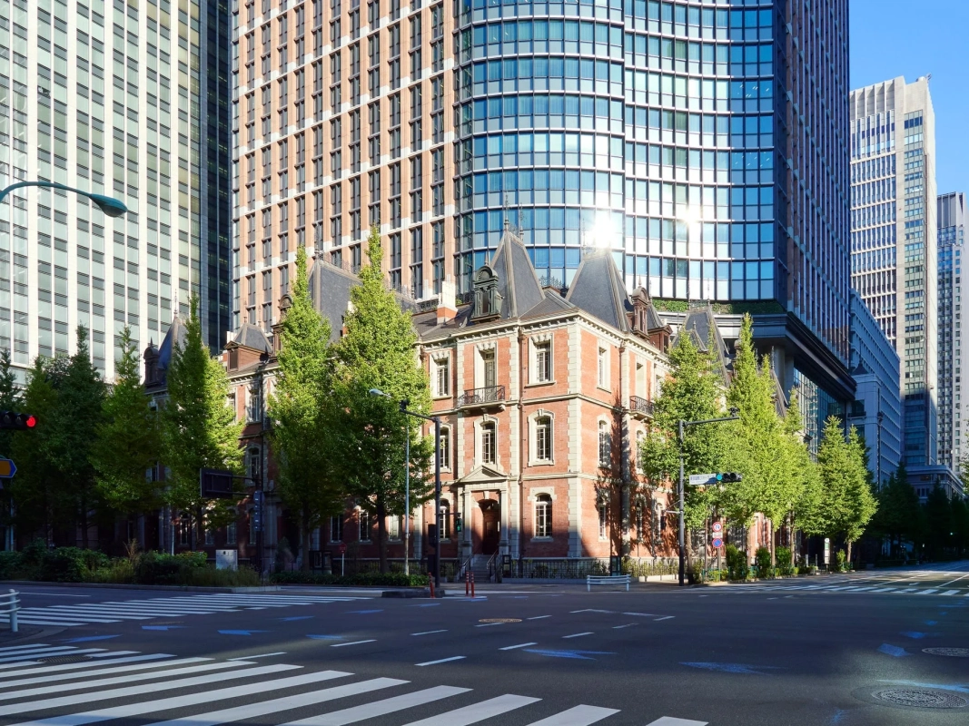 古い赤レンガの歴史的建造物が、現代的な高層ビル群と並んで立つ都市の風景