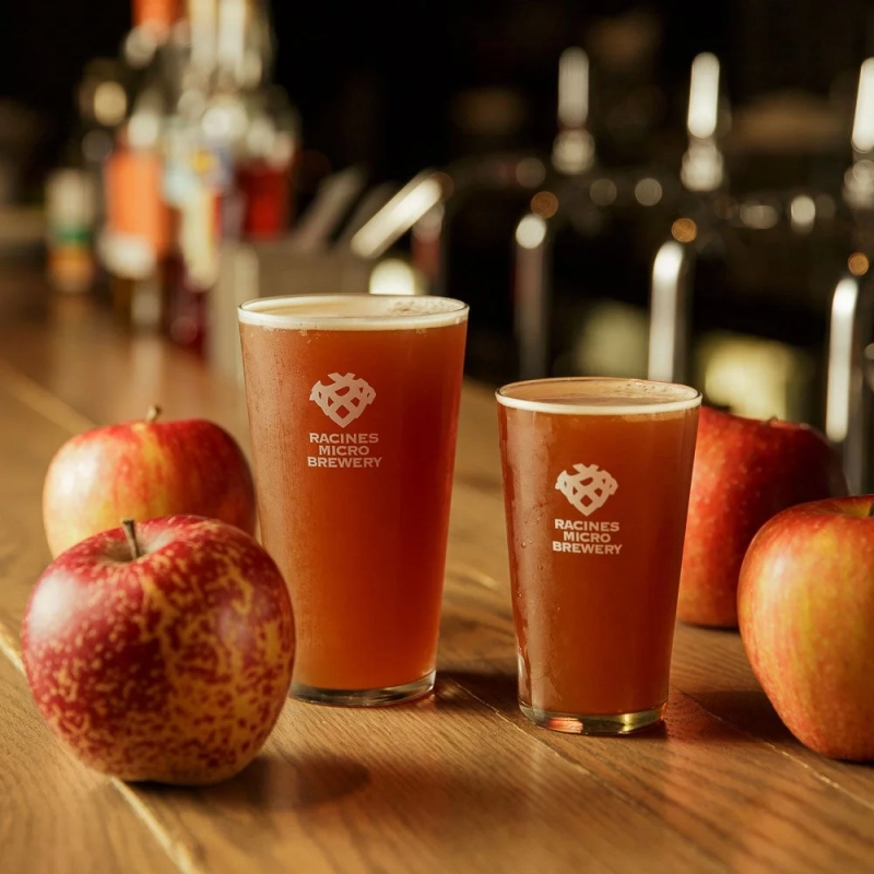 木製のテーブルに置かれた2つのグラスに入った琥珀色の飲み物と、リンゴ