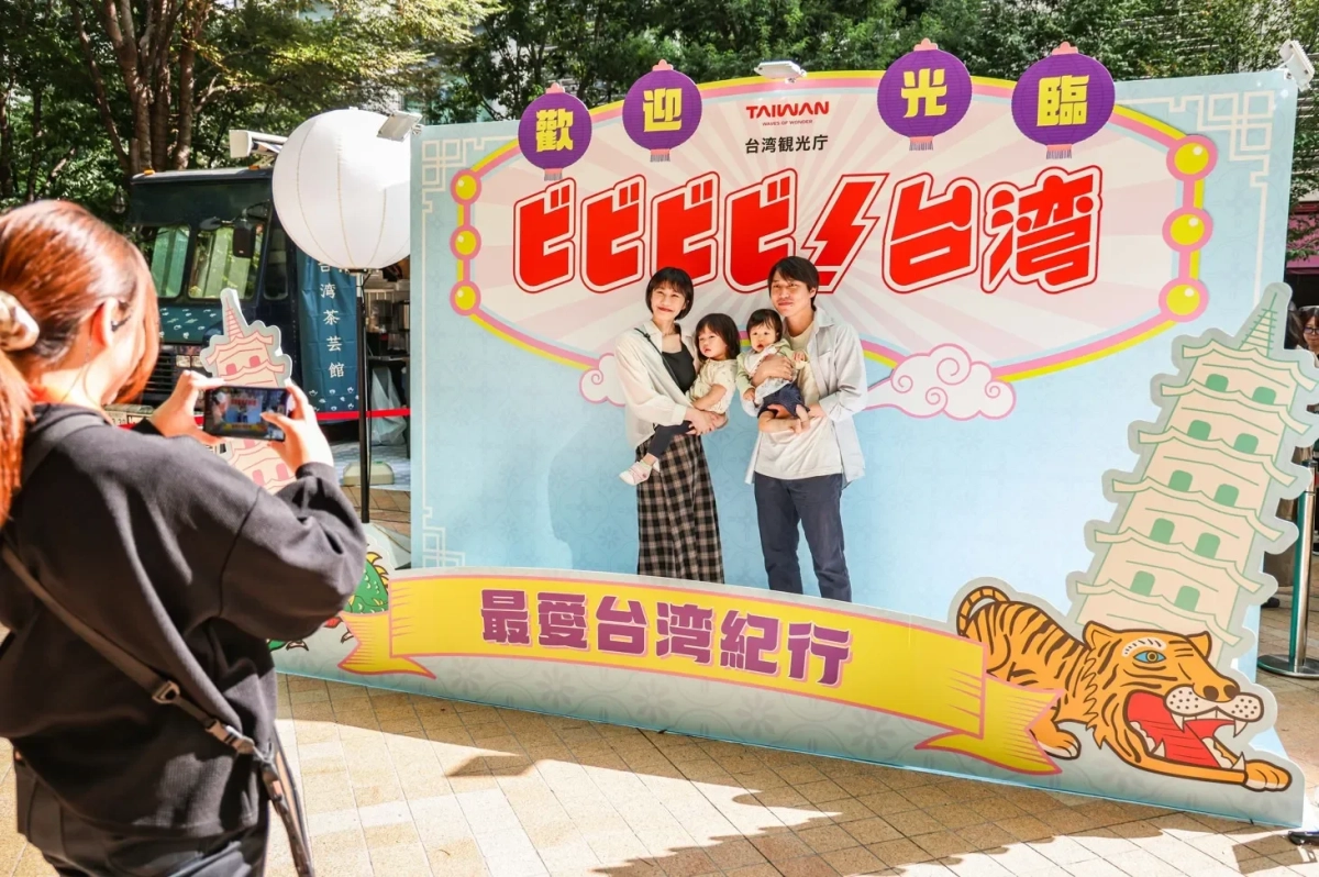 家族が台湾観光プロモーションの背景幕で写真撮影