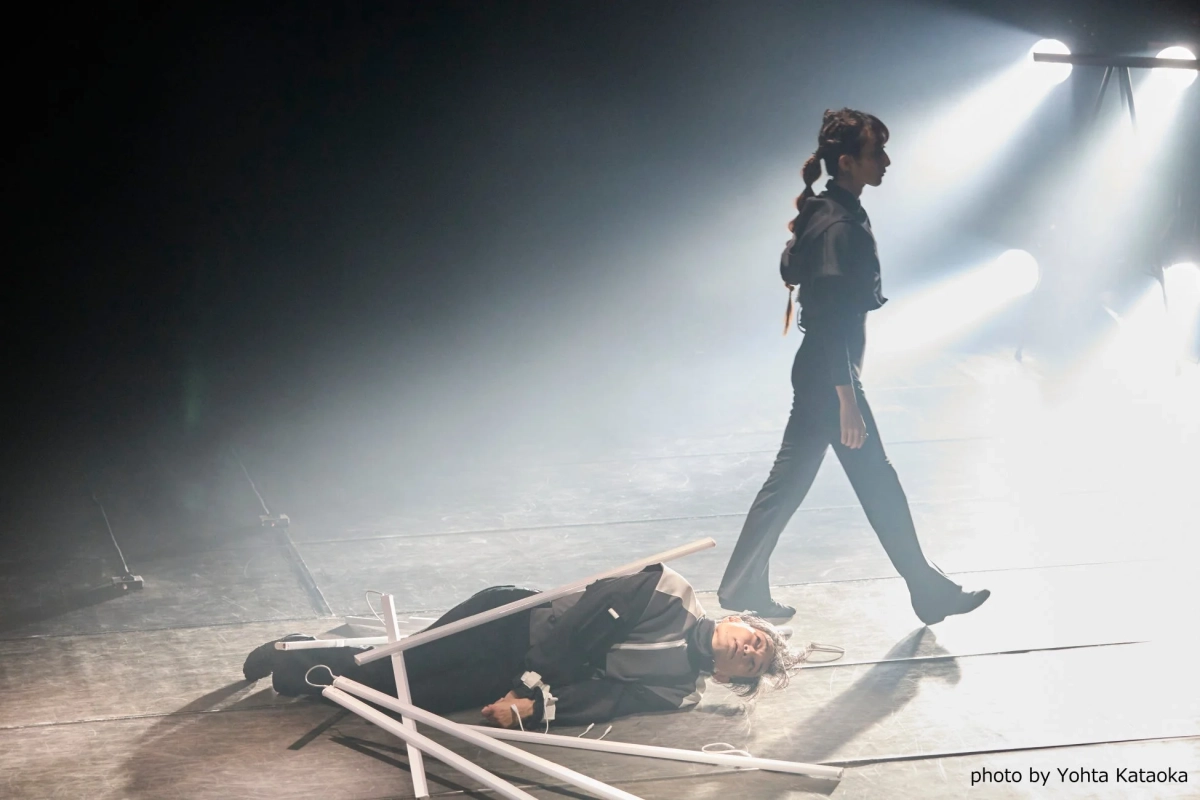 霧が立ち込める舞台、歩く人物と横たわる人物、動きと静止の対比
