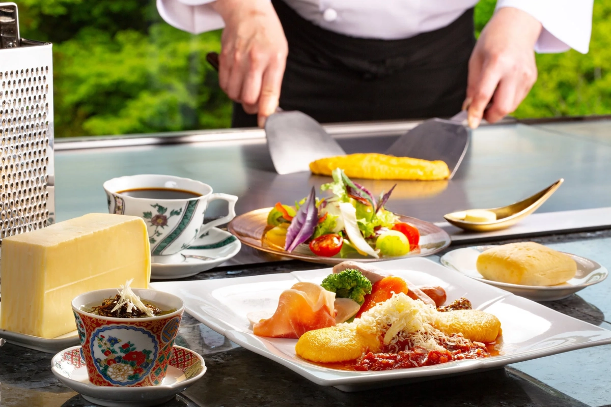 シェフが鉄板で調理する様子と、食卓に並べられた豪華な料理が写っています