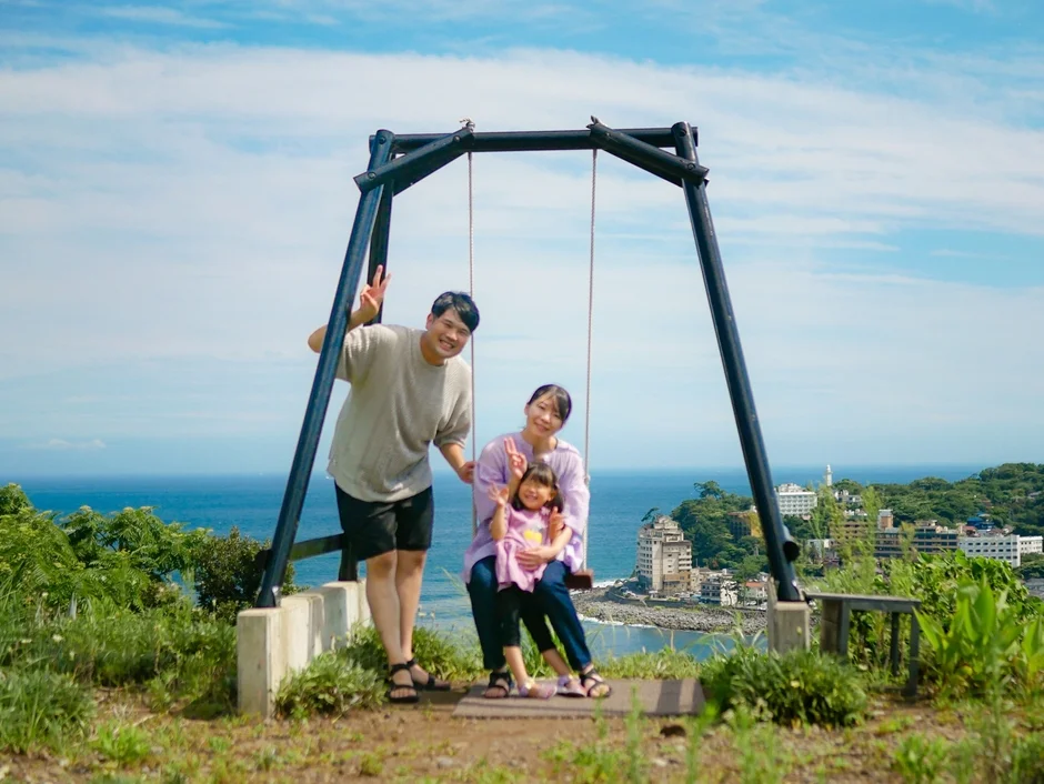 海を背景にブランコに乗る家族