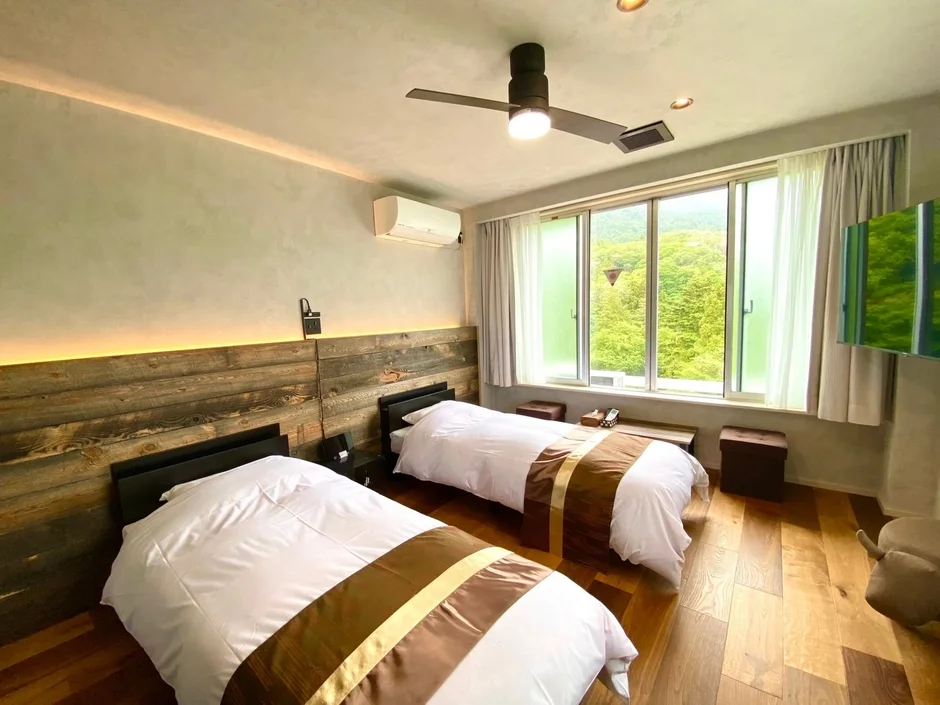 木製の壁とフローリングが特徴の、明るくモダンなツインルーム