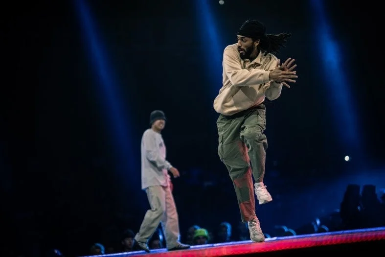 青い照明の下でパフォーマンスを披露する男性ダンサーたち