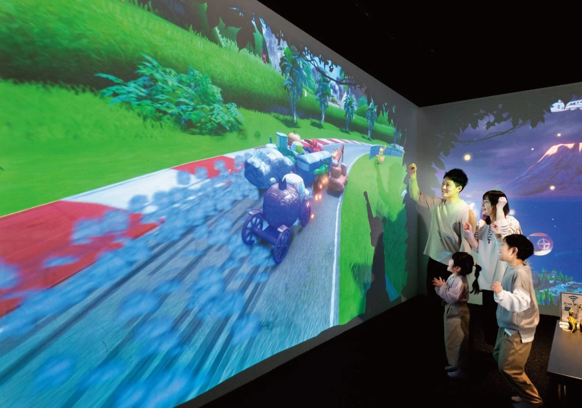 プロジェクションマッピングのレースゲームを楽しむ家族