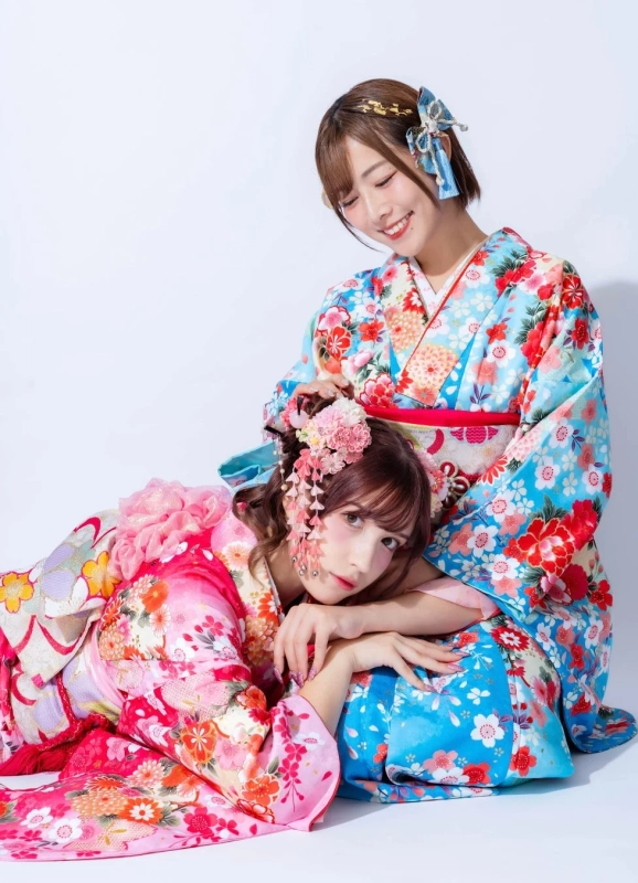 鮮やかな花柄の着物をまとった二人の女性が笑顔で寄り添い合うポートレート