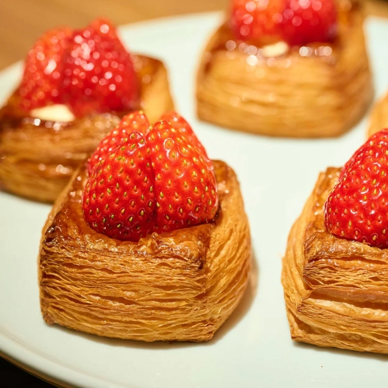 サクサクのデニッシュ生地の上に、真っ赤な新鮮ないちごがたっぷりと乗せられたペストリー