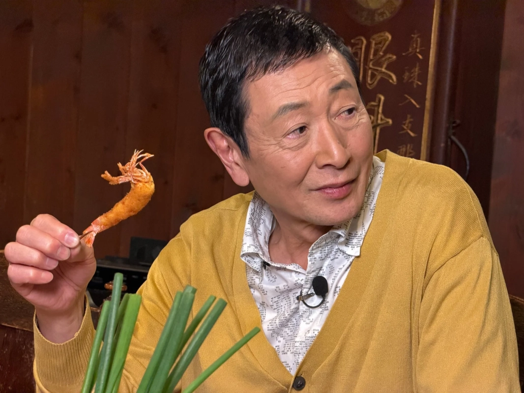 串に刺さったエビフライを持つ男性