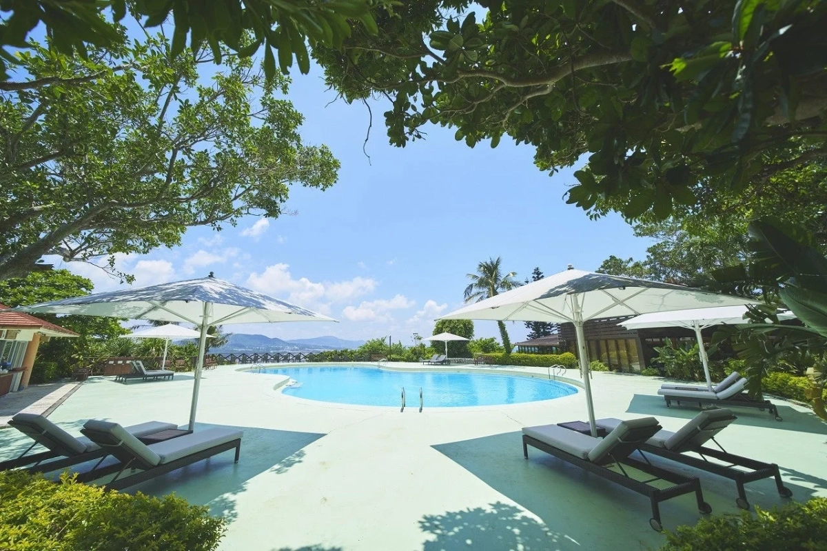 美しい青空の下、リゾートホテルの屋外プールエリアが広がっている