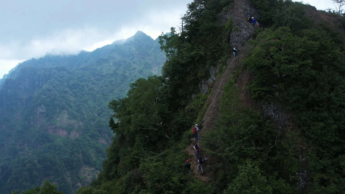 ロープを使って急峻な山道を登る