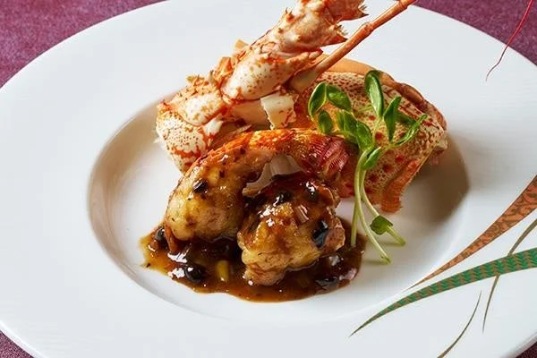 白い皿に盛り付けられたロブスターの尾と身を使った豪華なシーフード料理