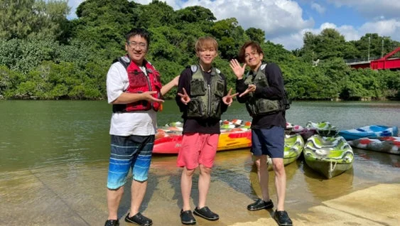 カヌーのそばで笑顔でポーズをとる3人の男性