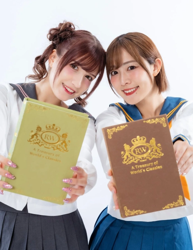 セーラー服を着た二人の女性が笑顔で本を掲げている