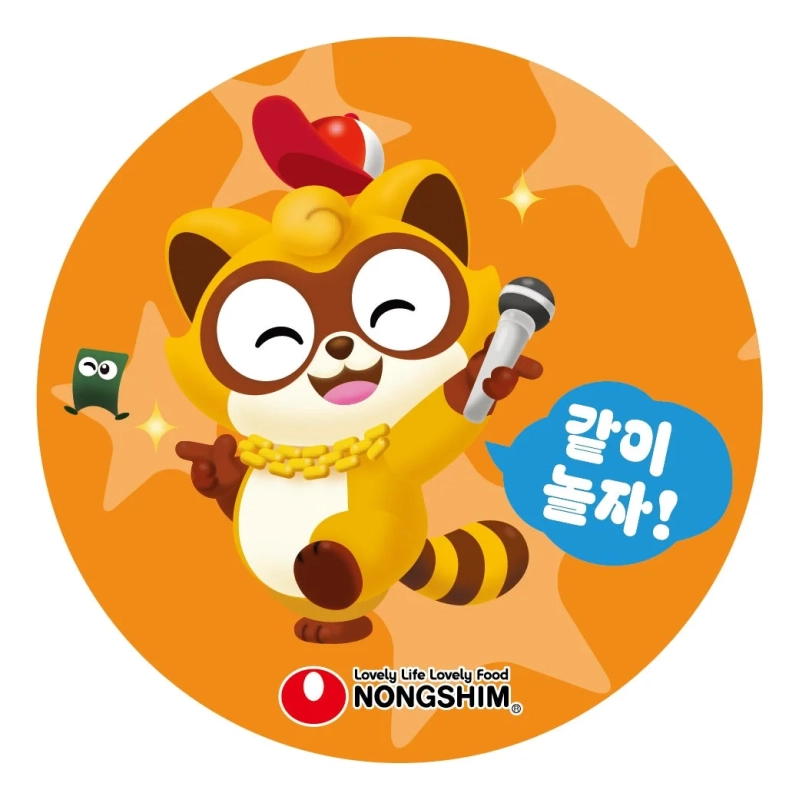 オレンジ色の背景に、赤い帽子と金のネックレスを身につけた陽気なタヌキのキャラクターが、マイクを持って歌いながら楽しそうにしているイラストです。「一緒に遊ぼう！」という韓国語の吹き出しと、農心のロゴが描かれています。