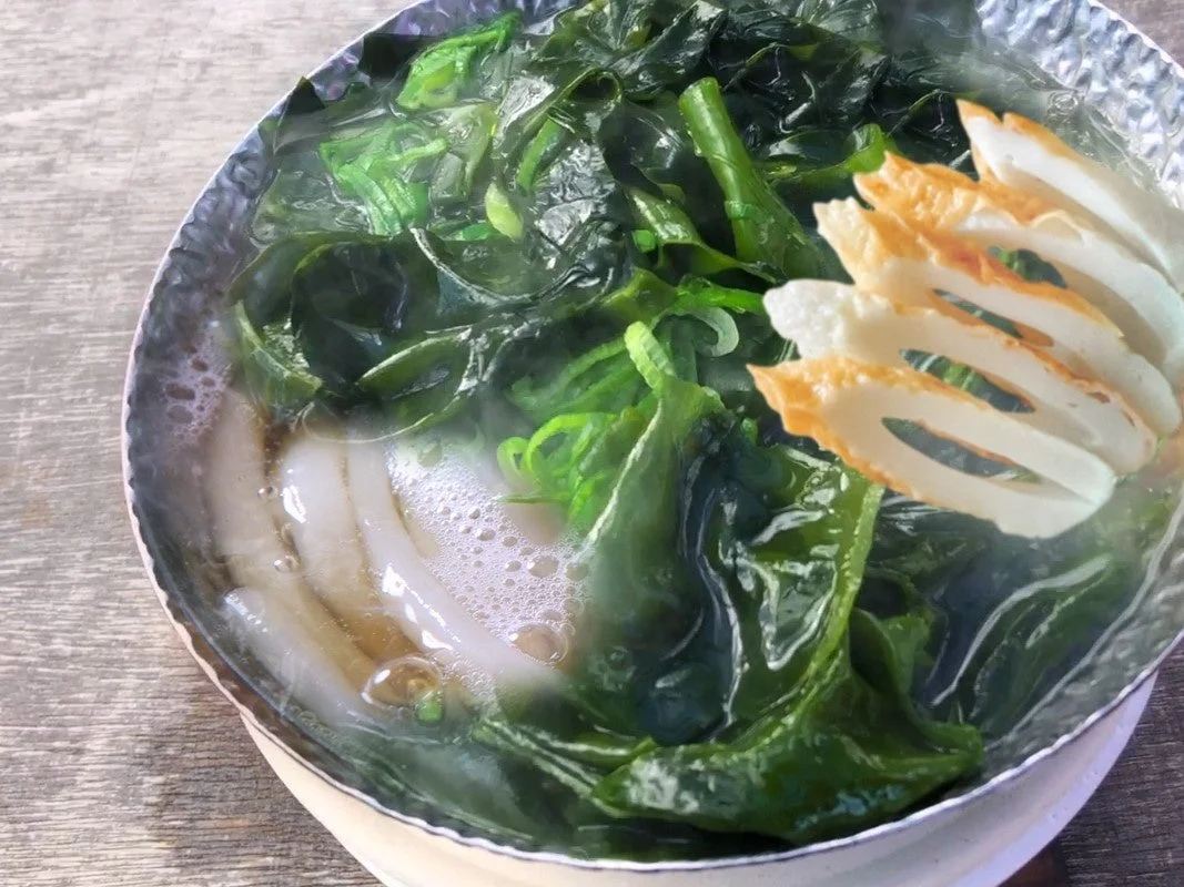 たっぷりのわかめと蒲鉾が乗った鍋焼きうどん