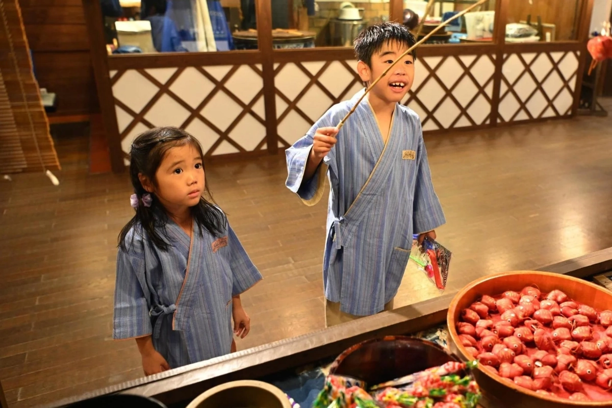 和服の子供たちが魚釣りゲームを楽しむ様子