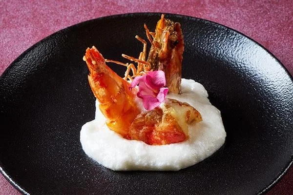 黒い皿に盛り付けられた香ばしい揚げ海老の料理