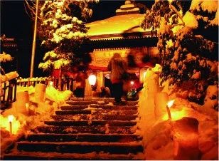 雪が積もった夜の寺院へ続く階段と雪灯籠