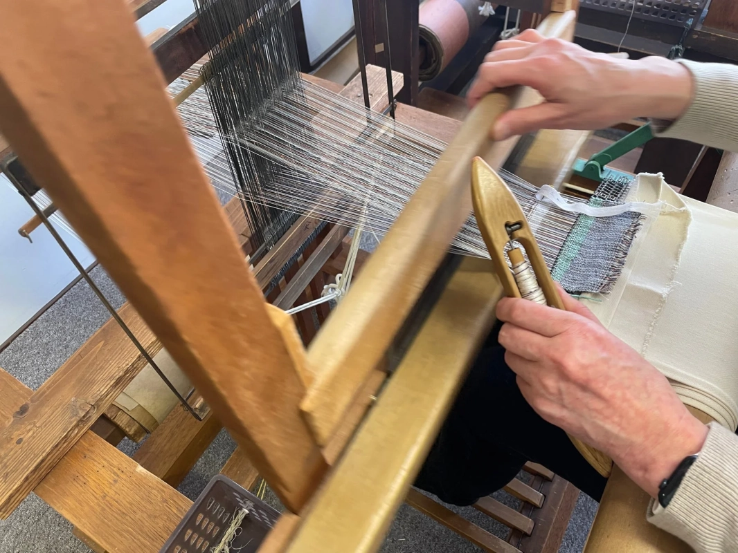 木製の織機を使って手織り作業をしている様子