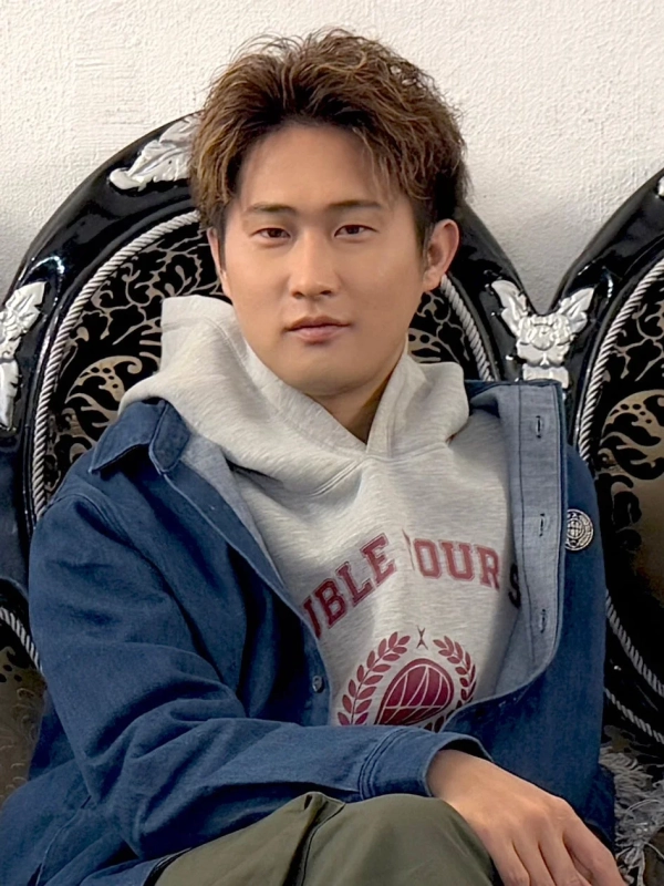 グレーのフーディーとデニムジャケットを着用した男性