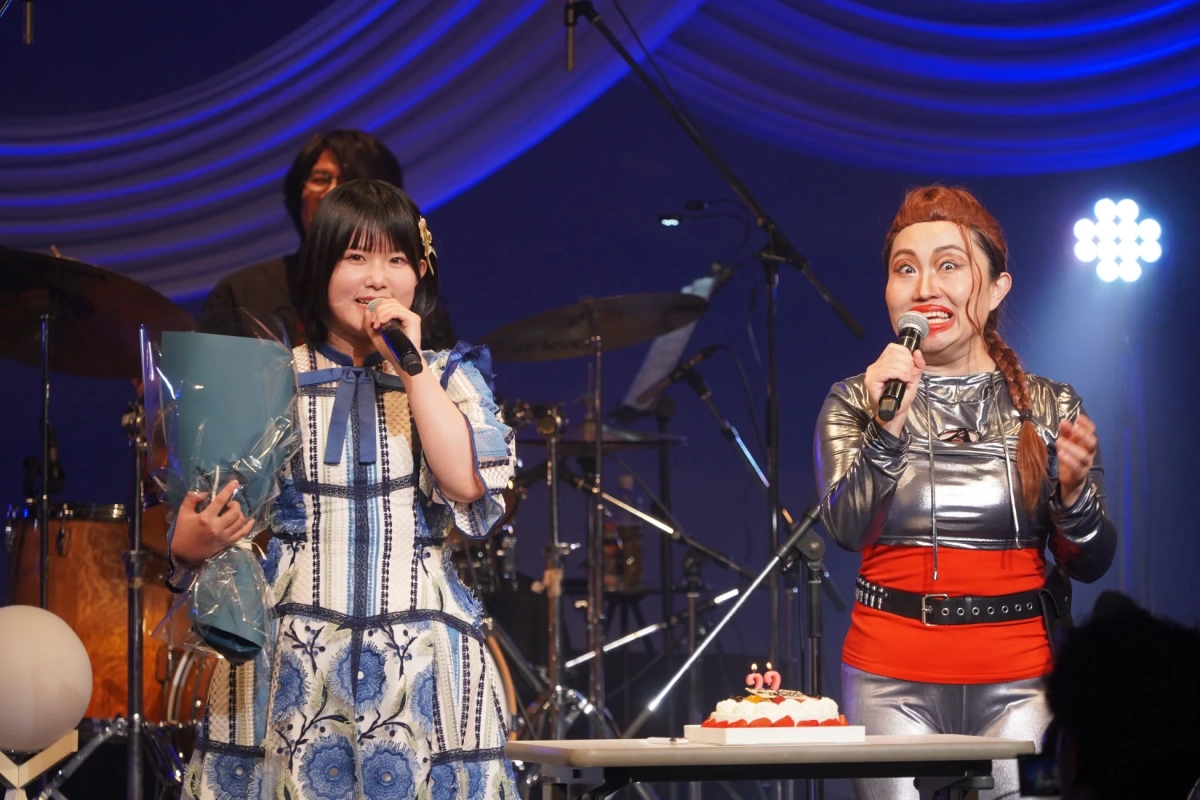 ステージ上で2人の女性がマイクを持ってパフォーマンスしている様子