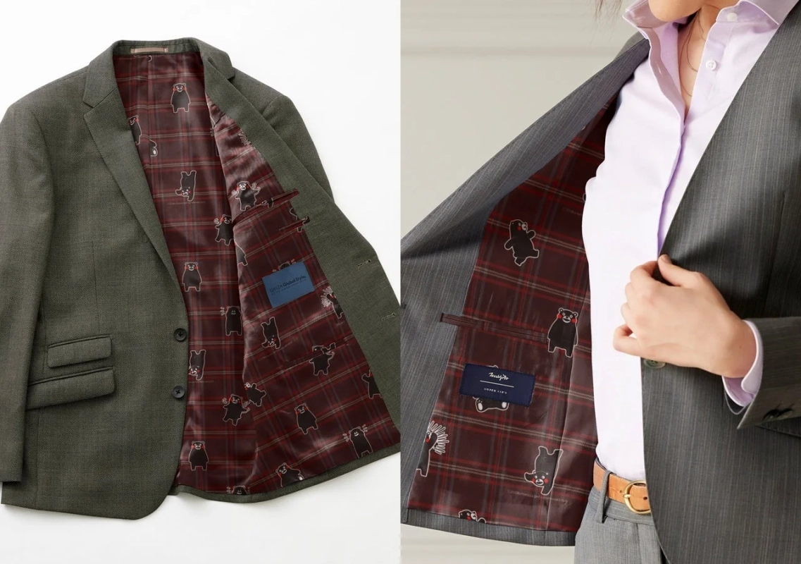 2着のスーツが写っており、どちらも赤系のチェック柄に黒いクマのキャラクター（クマモン）がデザインされた遊び心ある裏地が特徴です。1着は平置き、もう1着は着用されています。