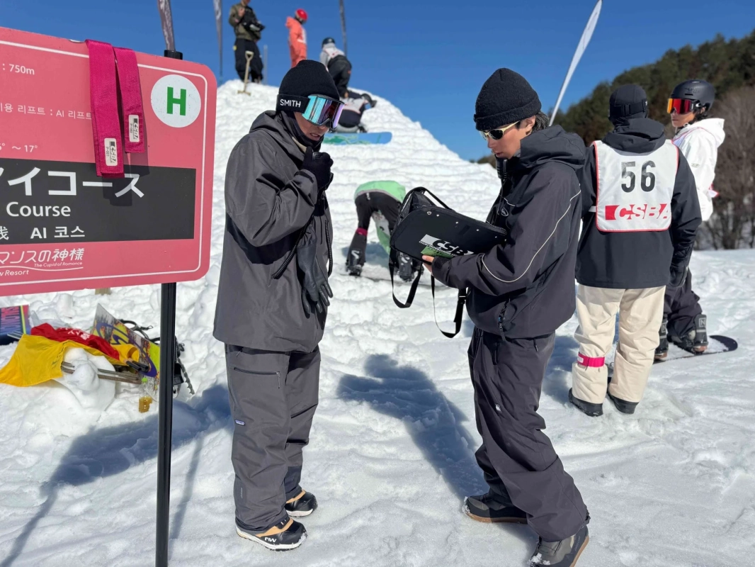 スキー場でコース案内板の近くに立つ2人の人物