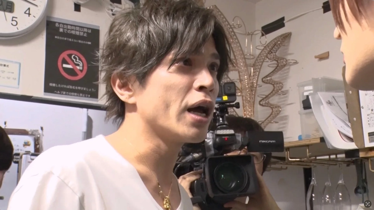 グレーヘアの男性が何かを話しており、その様子をカメラが撮影している