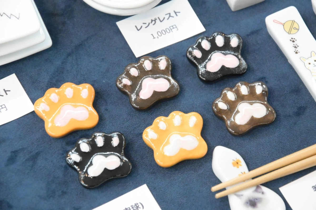猫の肉球を模した、オレンジ、黒、茶色のかわいい箸置き（レンゲレスト）が複数並べられています
