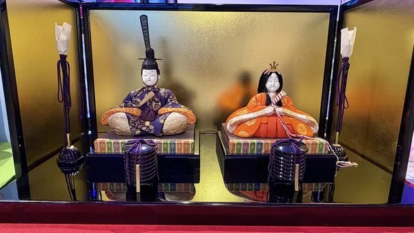 金屏風を背景に、お内裏様とお雛様が飾られた伝統的な雛人形のセットです。ひな祭りの飾り付けとして用いられます。