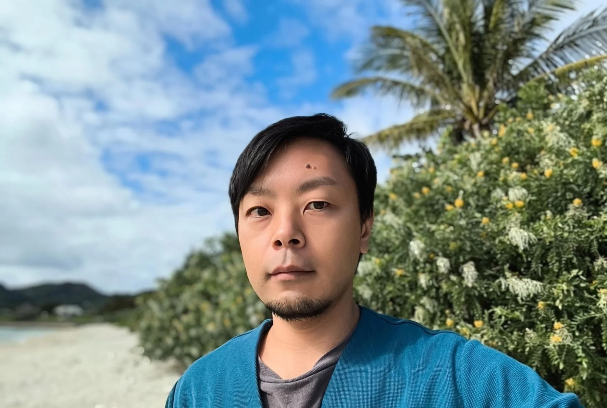 青いカーディガンを着た男性（山谷 健氏）