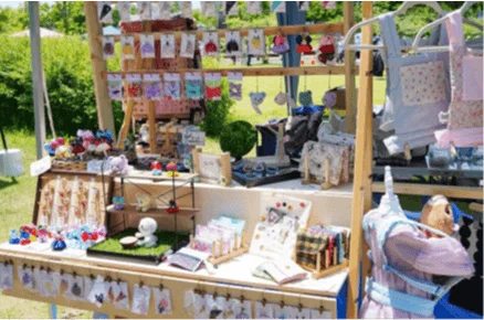 屋外の手作り市でハンドメイド雑貨が並べられている様子