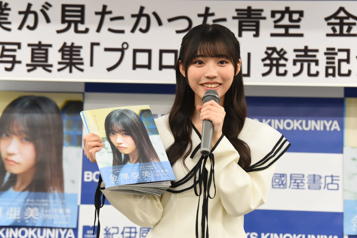 金澤亜美さんがマイクを持ち写真集を掲げる