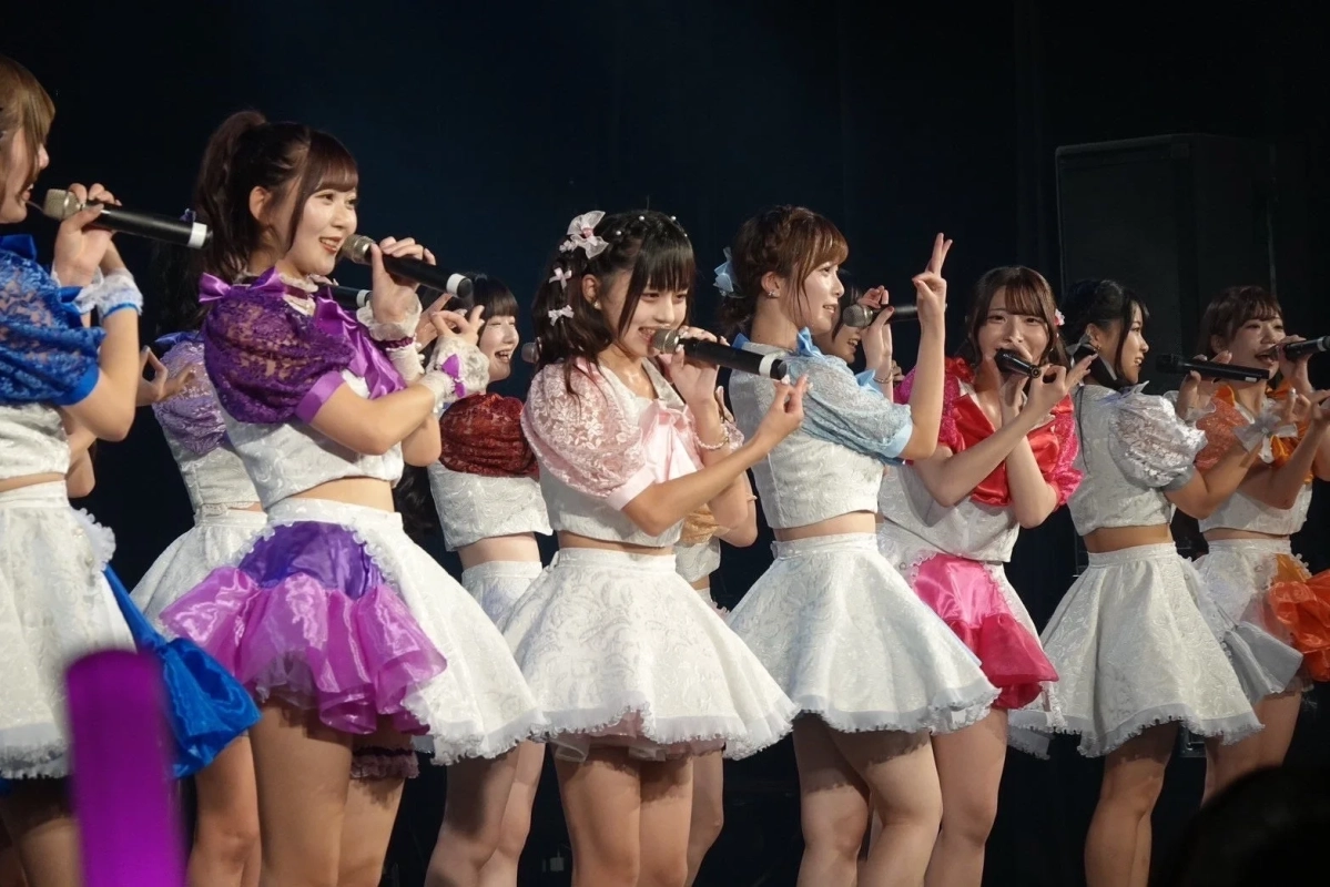ステージでマイクを持ちパフォーマンスする女性アイドルたち