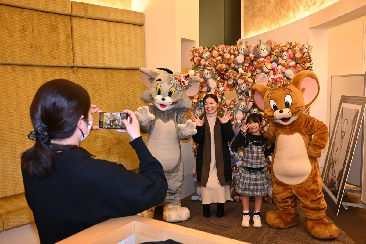 トムとジェリーのぬいぐるみが飾られたウォールで記念撮影をする人々の様子