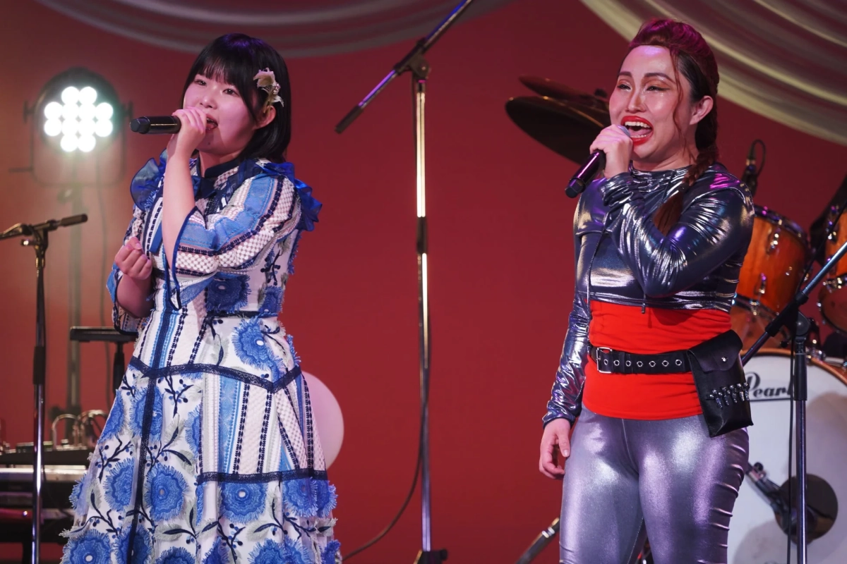 2人の女性がステージで歌唱している様子