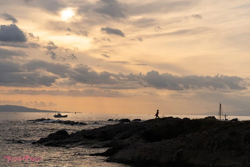 夕焼けの海岸線を歩く人物