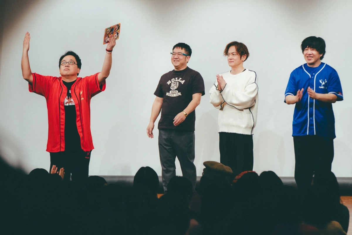 4人の男性がステージ上に立ち、観客から拍手を受けている様子
