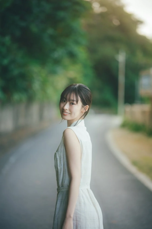 緑豊かな道で振り返る井本彩花さんの笑顔