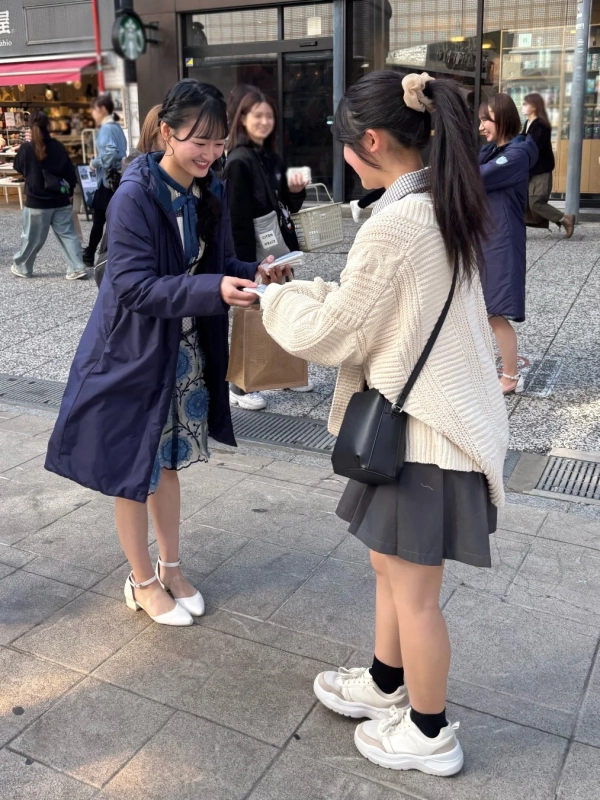 街中で笑顔でティッシュを配るSTU48メンバー