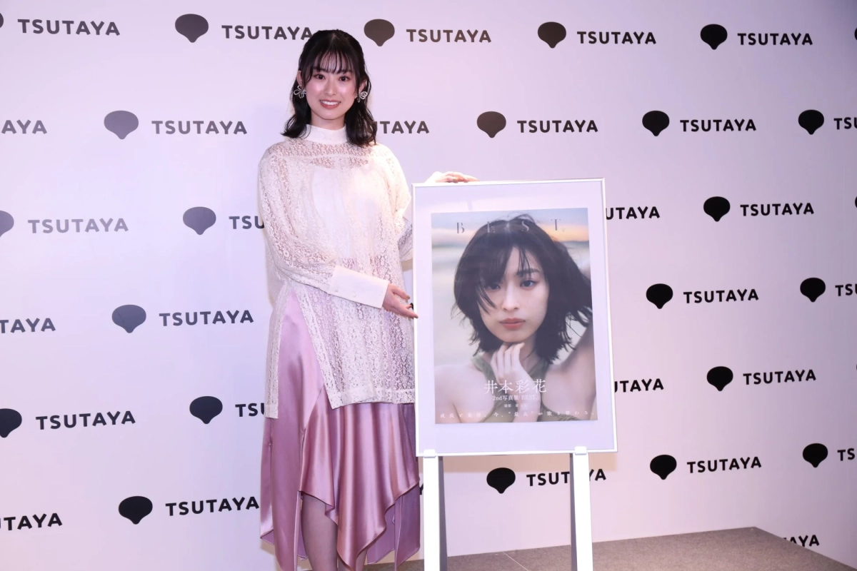 写真集のポスターの前で笑顔の井本彩花さん