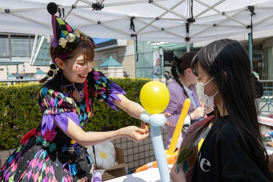 カラフルな衣装のパフォーマーがバルーンアートを作っている様子