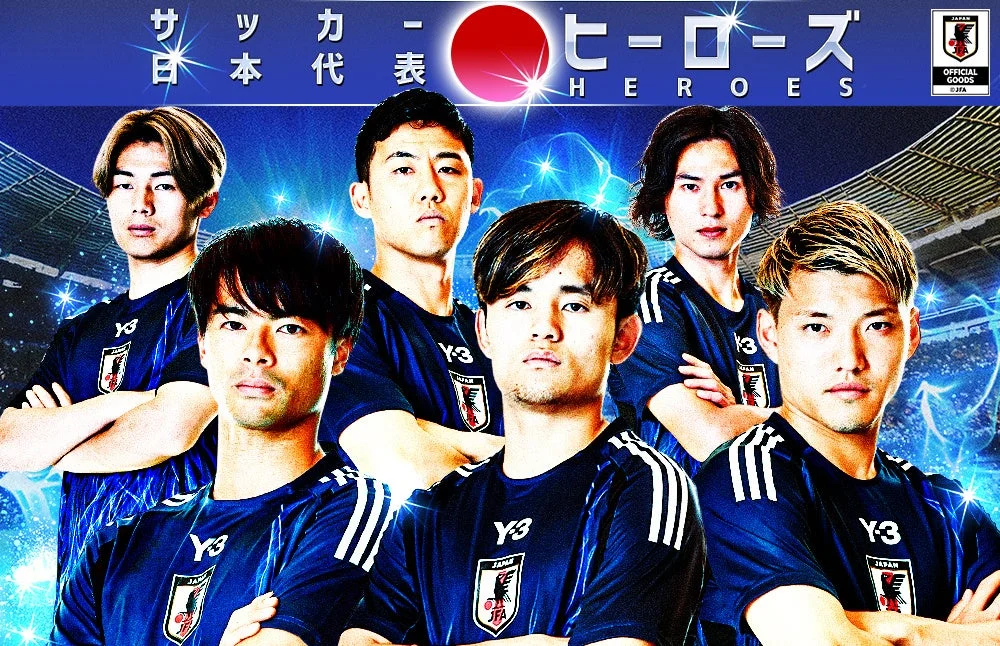 サッカー日本代表選手たちが青いユニフォームを着用し、スタジアムを背景にポーズ