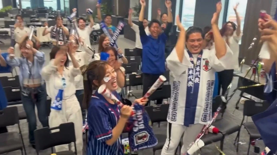 日本代表のユニフォームやグッズを身につけ、腕を上げて歓声を上げている人々